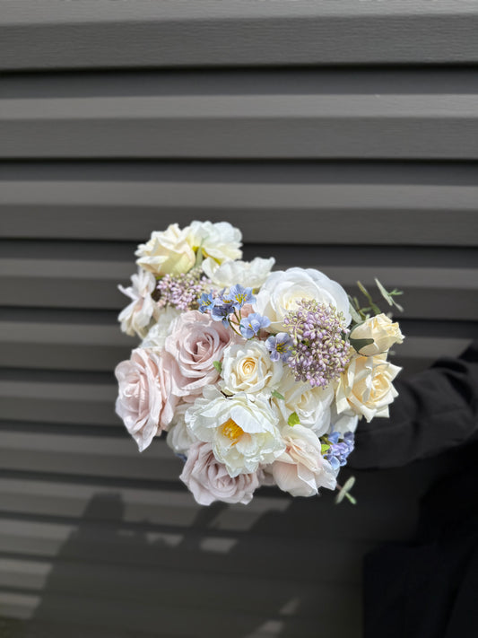 Pastel bridal bouquet with cream roses, garden roses and delicate blue accents. Classic and perfect