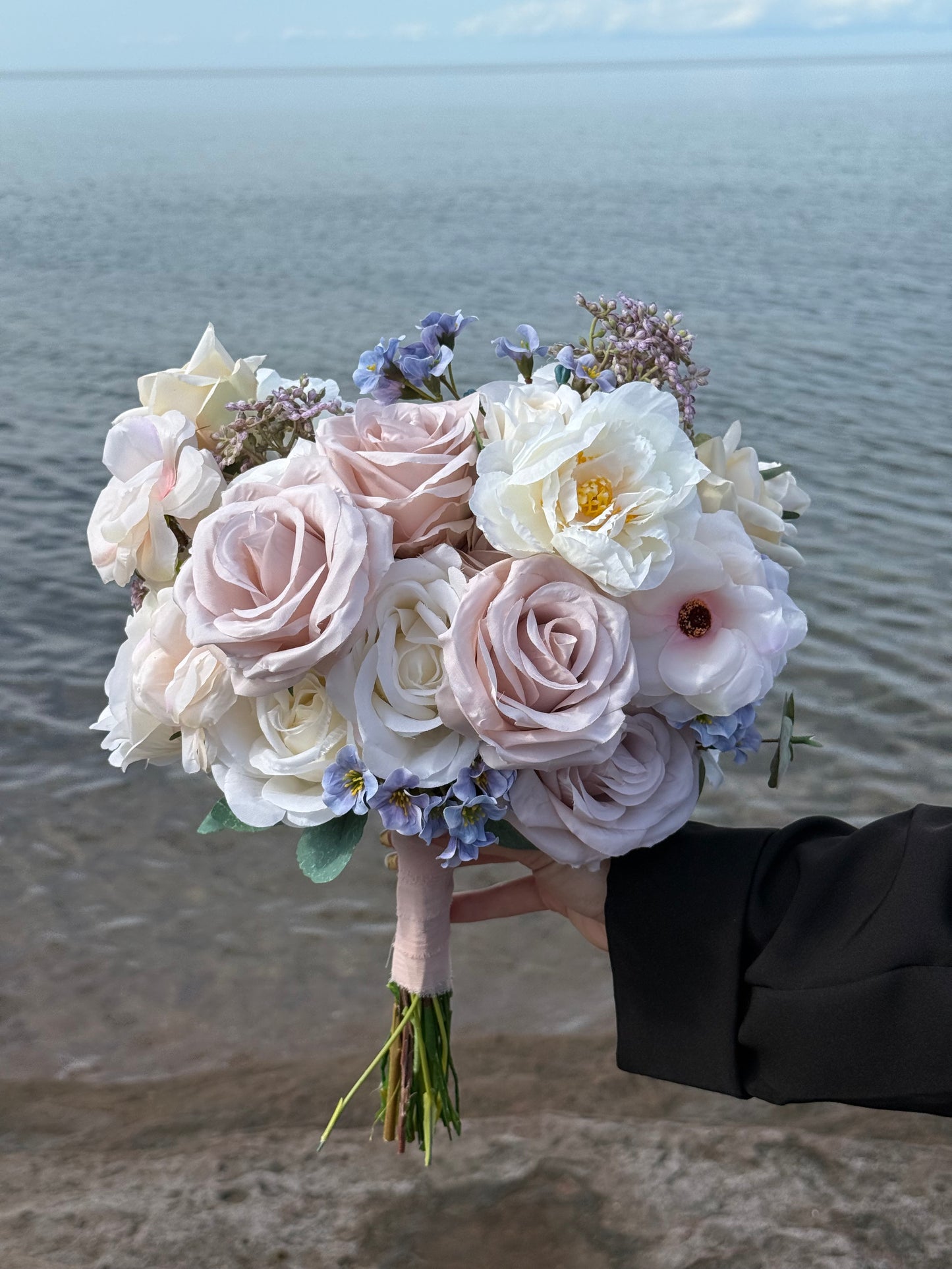 Pastel bridal bouquet with cream roses, garden roses and delicate blue accents. Classic and perfect